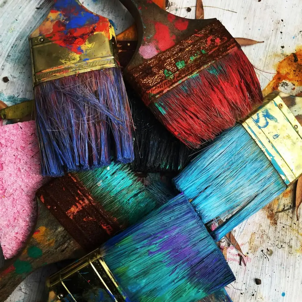 Well used paint brushes covered in bright colours, ready for tree artwork